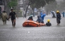 Local residents move hotel guests using a rubber boat through the water on an inundated street amid floods following heavy rain at Legian Kuta near Denpasar on Indonesia's resort island of Bali on February 24, 2026. (Photo by SONNY TUMBELAKA / AFP)