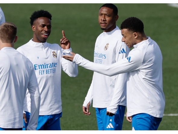 Real Madrid's Brazilian forward #07 Vinicius Junior (L) talks with Real Madrid's French forward #10 Kylian Mbappe (R) during a training session on the eve of their UEFA Champions League knockout round play-off second leg football match against SL Benfica at Santiago Bernabeu Stadium at Real Madrid Sports City in Valdebebas, in the outskirts of Madrid on February 24, 2026. (Photo by Oscar DEL POZO / AFP)