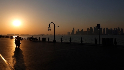 A man is silhouetted by the setting sun as he rides his motorcycle in Doha's Mina district on February 26, 2026. (Photo by Karim Jaafar / AFP)