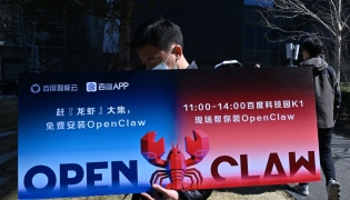 A man holds a placard featuring OpenClaw, an open-source AI assistant, during an event at the Baidu headquarters in Beijing on March 11, 2026. Photo by ADEK BERRY / AFP