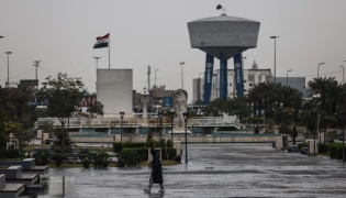 An Iraqi man walks through Al-Umma Park during rainfall in Baghdad on March 15, 2026. (Photo by AHMAD AL-RUBAYE / AFP)
