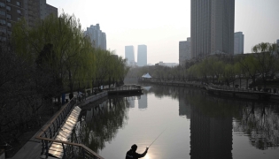 An angler fishes by the Liangma River on a spring day in Beijing on March 24, 2026. (Photo by Pedro Pardo / AFP)
 