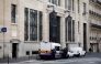 Police officials stand alongside police and private security vehicles outside The Bank of America building in the 8th arrondissement of Paris on March 28, 2026, following an apparent bomb attack attempt. (Photo by Sebastien Dupuy / AFP)