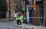 Police officers work near to a variety of personal items seen covering the road inside a cordon set up on Friar Gate in central Derby, central England on March 29, 2026. (Photo by Darren Staples / AFP)