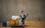 A displaced Palestinian boy stands on a trolley loaded with empty water canisters at the Nuseirat refugee camp, in the central Gaza Strip on April 1, 2026. (Photo by Eyad Baba / AFP)