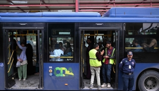 Passengers gather aboard a government bus at a bus stop in Islamabad on April 3, 2026. Photo by Farooq NAEEM / AFP