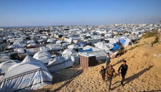 Boys walk past the tents at a makeshift camp for displaced Palestinians in Khan Yunis, in the southern Gaza Strip on April 10, 2026. (Photo by Bashar Taleb / AFP)
