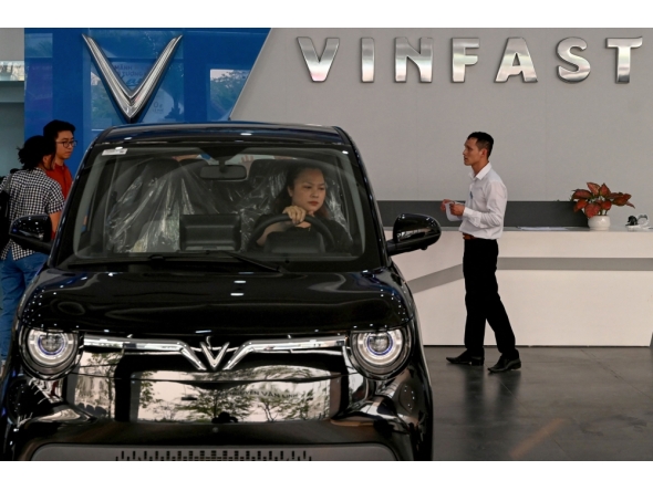 This photo taken on April 11, 2026, shows a woman behind the wheel of a car inside a Vinfast electric car dealership in Hanoi. (Photo by Nhac Nguyen / AFP)