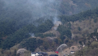 A fire engine sprays water on a hill side near homes in the town of Otsuchi, in Iwate Prefecture on April 25, 2026.(Photo by Andrew Caballero-Reynolds / AFP)