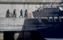 Persons wearing protective suits walk toward the hantavirus-stricken cruise ship MV Hondius docked in the port of Granadilla de Abona on the island of Tenerife in Spain's Canary Islands on May 11, 2026. (Photo by JORGE GUERRERO / AFP)