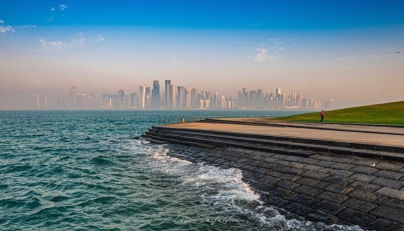 A runner is seen exercising along the Doha Corniche as waves splash along the shoreline e, with Doha's skyline standing prominently in the background. Pic: Qatarweather