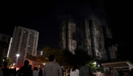 Bystanders look on after a major fire swept through several apartment blocks at the Wang Fuk Court residential estate in Hong Kong's Tai Po district on November 27, 2025. Photo by Philip FONG / AFP