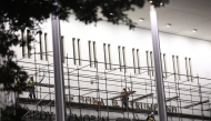 Workers build scaffolding near the signage for the 