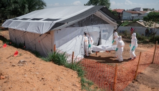 Members of specialized response teams enter the morgue of the Evangelical Medical Center of Nyankunde (CME) with the body of a person who died from Ebola virus disease to allow relatives to pay their last respects after washing, disinfection and safe body-wrapping procedures in Bunia, Ituri Province, Democratic Republic of Congo, on June 13, 2026. (Photo by Jospin Mwisha / AFP)