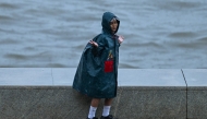 A child enjoys during rainfall while going to school, in Mumbai on June 23, 2026. (Photo by Punit Paranjpe/ AFP)
