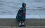 A child enjoys during rainfall while going to school, in Mumbai on June 23, 2026. (Photo by Punit Paranjpe/ AFP)
