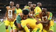 South Africa's forward #12 Thapelo Maseko is hugged by teammates while celebrating scoring his team's first goal. (Photo by Yuri Cortez / AFP)
