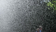 A man and woman walk past the water stream of a sprinkler system at the WTA 500 Bad Homburg Open tennis tournament in Bad Homburg, western Germany on June 25, 2026. (Photo by Kirill KUDRYAVTSEV / AFP)
 