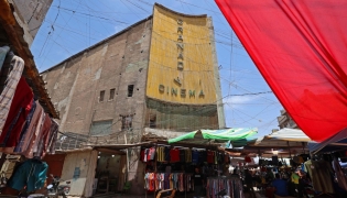Street vendors gather outside the faded facade of the Granada Cinema, an early 1940s landmark, in the Bab al-Sharqi district of central Baghdad on May 26, 2026. (Photo by Ahmad Al-Rubaye/ AFP)