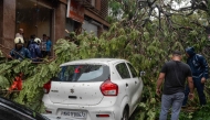 Civic-authority workers clear the road, blocked by uprooted trees following strong winds and heavy rainfall in Mumbai on July 5, 2026. (Photo by Punit Paranjpe / AFP