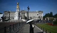 A person uses a parasol umbrella to shelter from the heat of the sun during a heatwave, as they walk near Buckingham Palace, in central London on July 7, 2026. (Photo by Justin Tallis / AFP)