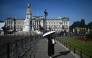 A person uses a parasol umbrella to shelter from the heat of the sun during a heatwave, as they walk near Buckingham Palace, in central London on July 7, 2026. (Photo by Justin Tallis / AFP)