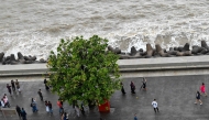 This photograph taken on July 7, 2026 shows pedestrians walking on the footpath along the seafront in Mumbai. (Photo by Punit Paranjpe / AFP)