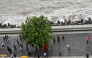 This photograph taken on July 7, 2026 shows pedestrians walking on the footpath along the seafront in Mumbai. (Photo by Punit Paranjpe / AFP)