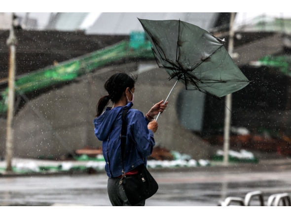 A woman struggles with an umbrella in strong winds and rain as typhoon Bavi passes off northeastern Taiwan in Keelung on July 11, 2026. More than 14,000 people in Taiwan have fled their homes, and many shops remain closed, as a typhoon pounding Japan's remote southwestern islands swept towards China on July 11. (Photo by I-Hwa Cheng / AFP)