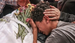 A relative mourns over the body of 17-year-old Fadi al-Naasan during his funeral in the village of Al-Mughayyir, east of Ramallah in the Israeli-occupied West Bank, on July 18, 2026. (Photo by JAAFAR ASHTIYEH / AFP)