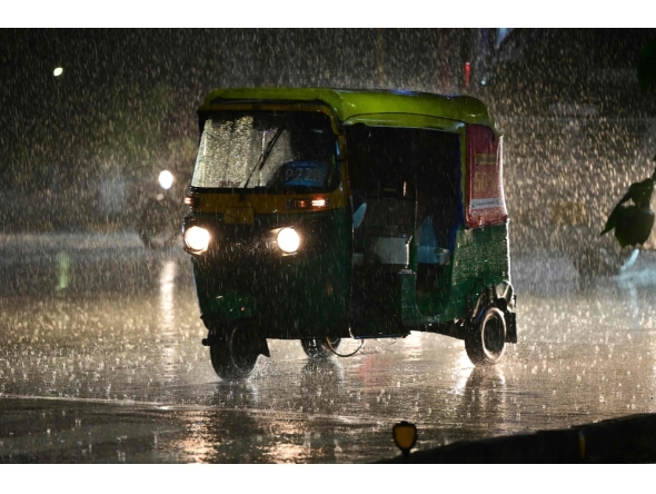 Commuters ride along a street during rainfall in Ahmedabad on July 18, 2026. (Photo by Shammi MEHRA / AFP)