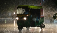 Commuters ride along a street during rainfall in Ahmedabad on July 18, 2026. (Photo by Shammi MEHRA / AFP)
