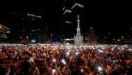 Spain's supporters turn on their phone flashlight as they watch the 2026 World Cup final match between Spain and Argentina displayed on giant screens underneath the Christopher Columbus statue on Colon square's in Madrid, on July 19, 2026. (Photo by Paul Hanna / AFP)