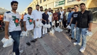 Volunteers from Qatar Probashi Bondhushava distribute refreshments among delivery riders.