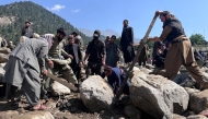Afghan men search the debris of destroyed shops following flash floods in Parun town in Afghanistan's Nuristan province, on July 21, 2026. (Photo by AFP)