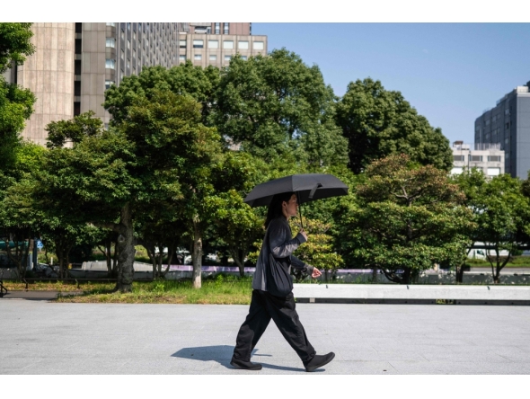 A man wearing all black walks through a park with an umbrella in Tokyo on July 22, 2026. (Photo by Andrew Caballero-Reynolds / AFP)