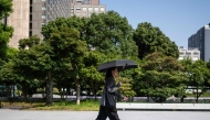 A man wearing all black walks through a park with an umbrella in Tokyo on July 22, 2026. (Photo by Andrew Caballero-Reynolds / AFP)