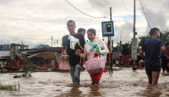 Residents wade through a flooded street near an overflowing river after heavy rains at Nambol in Bishnupur district, in India's northeastern state of Manipur on July 22, 2026. (Photo by Vishma Ahanthem / AFP)