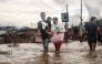 Residents wade through a flooded street near an overflowing river after heavy rains at Nambol in Bishnupur district, in India's northeastern state of Manipur on July 22, 2026. (Photo by Vishma Ahanthem / AFP)