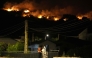 Residents watch the flames on hill crests as firefighters battle a wildfire in Cebreros area, near Avila, 80 kms west of Madrid at night on July 24, 2026. (Photo by Cesar MANSO / AFP)