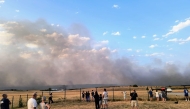 Bystanders look on as fire and smoke billow across Castres-Mazamet aerodrome, near Labruguiere in south-western France on July 24, 2026. (Photo by Daniel ABELOUS / AFP)

