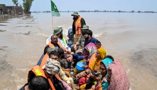 People sitting on a rescue boat ride through a flooded area after heavy monsoon rains induced a rise in the water level of the River Ravi in Muridke on July 27, 2026. (Photo by Arif ALI / AFP)