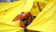 A school girl takes shelter under an umbrella at Jantar Mantar in New Delhi on July 24, 2026. (Photo by Arun Sankar / AFP)
 