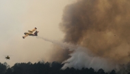 This aerial view taken from a Civil Security helicopter shows an aircraft dropping a load of water over a wildfire near Saint-Jean-d'Illac, southwestern France, on July 28, 2026. (Photo by Baz Ratner / POOL / AFP)