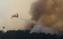 This aerial view taken from a Civil Security helicopter shows an aircraft dropping a load of water over a wildfire near Saint-Jean-d'Illac, southwestern France, on July 28, 2026. (Photo by Baz Ratner / POOL / AFP)