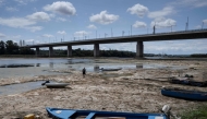 A fisherman tries to move his boat, blocked by algae on the bottom of the Danube river in front of the Calafat-Vidin bridge, connecting Bulgaria and Romania near the village Antimovo, southeastern Bulgaria, on July 22, 2026. (Photo by Nikolay DOYCHINOV / AFP)