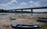 A fisherman tries to move his boat, blocked by algae on the bottom of the Danube river in front of the Calafat-Vidin bridge, connecting Bulgaria and Romania near the village Antimovo, southeastern Bulgaria, on July 22, 2026. (Photo by Nikolay DOYCHINOV / AFP)