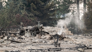 A burned motorcycle sits in the ashes of burned out residential home in the Balboa neighborhood of Spokane, Washington, on August 2, 2026. (Photo by Erick Doxey / AFP)
 
