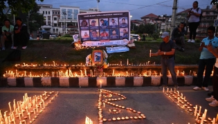 Mourners light candles before the portraits of mountaineer Nirmal Purja and his companions, who were killed in an avalanche in Pakistan, during a memorial ceremony in Kathmandu on August 4, 2026. (Photo by Prakash MATHEMA / AFP)