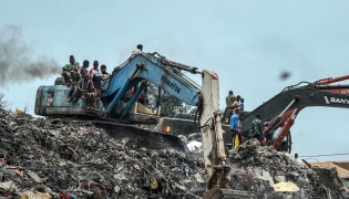 Residents and rescuers use an excavator to search for bodies after a landslide struck the Dar es Salaam dumpsite overnight in Conakry on August 23, 2026. (Photo by AFP)